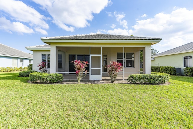 view of front of house with central air condition unit, a sunroom, a front lawn, and stucco siding