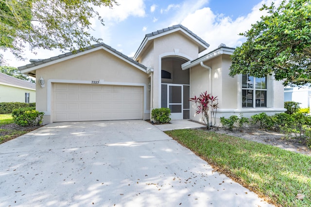 view of front of home with a garage, driveway, and stucco siding