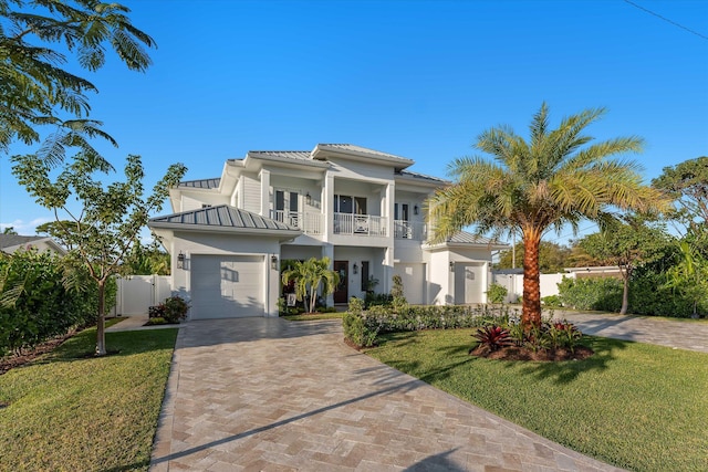 view of front facade featuring decorative driveway, a standing seam roof, metal roof, and a balcony