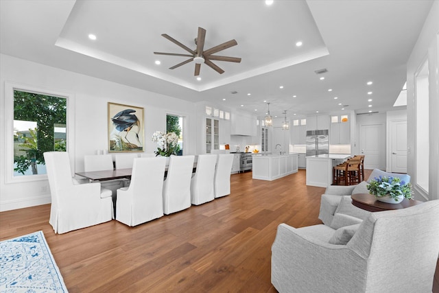 dining area with wood finished floors, a raised ceiling, and a wealth of natural light