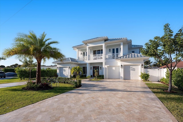 view of front of property with decorative driveway, a standing seam roof, metal roof, a balcony, and fence