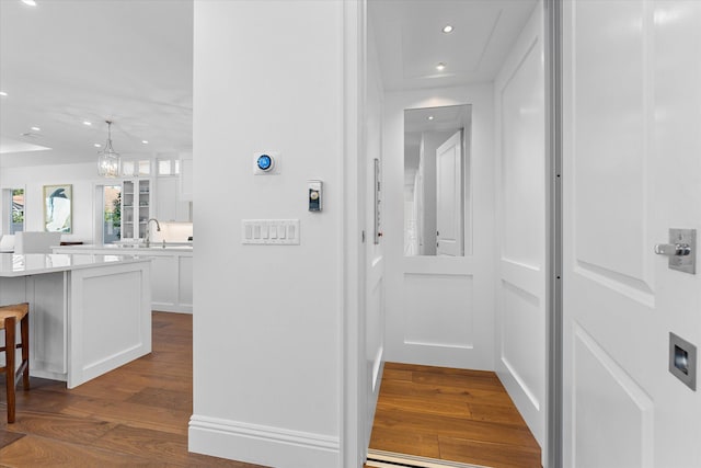 hall featuring a sink, dark wood finished floors, and recessed lighting