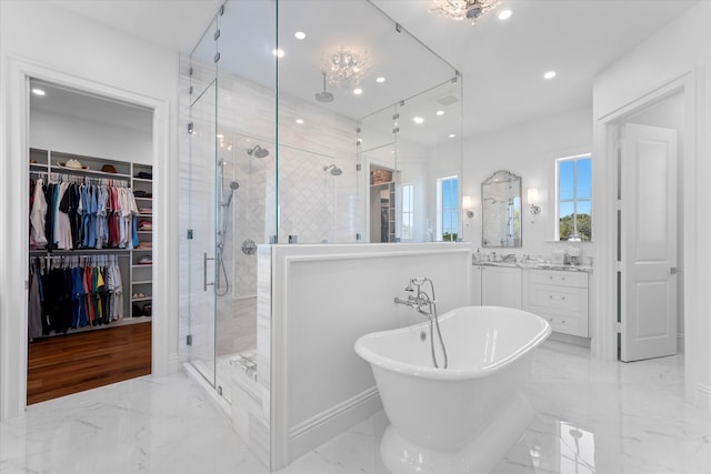 full bathroom with a stall shower, marble finish floor, a spacious closet, vanity, and a freestanding tub