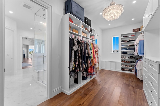 spacious closet with hardwood / wood-style flooring, visible vents, and a chandelier