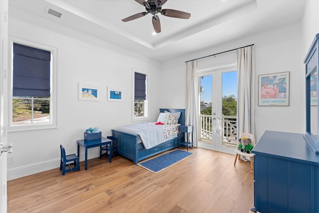 bedroom featuring access to exterior, light wood-style flooring, visible vents, and a raised ceiling