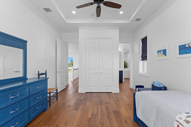 bedroom with dark wood-style floors, visible vents, a tray ceiling, and recessed lighting