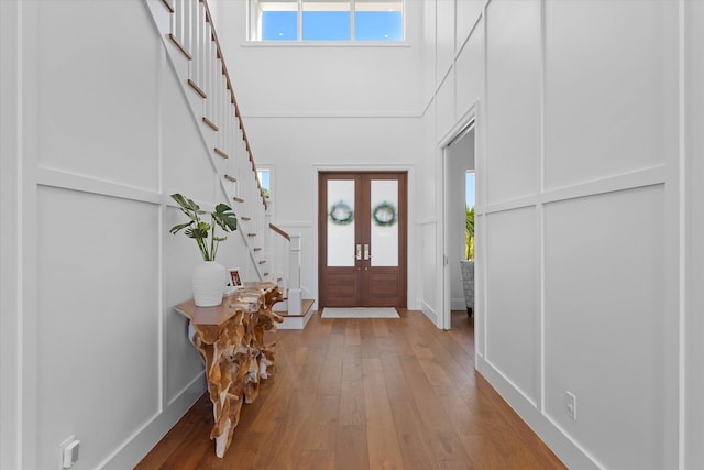 entrance foyer with hardwood / wood-style floors, stairway, plenty of natural light, and a decorative wall