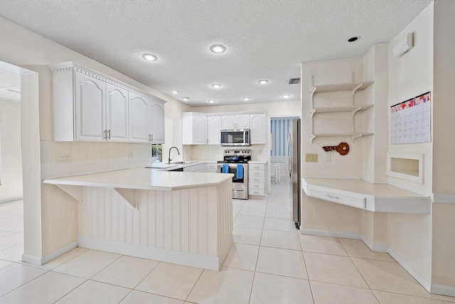 kitchen featuring light tile patterned floors, open shelves, a peninsula, stainless steel appliances, and light countertops