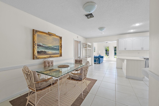 dining space with light tile patterned flooring, visible vents, and a textured ceiling