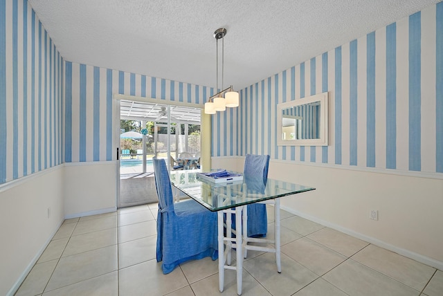 dining area featuring tile patterned floors, baseboards, a textured ceiling, and wallpapered walls