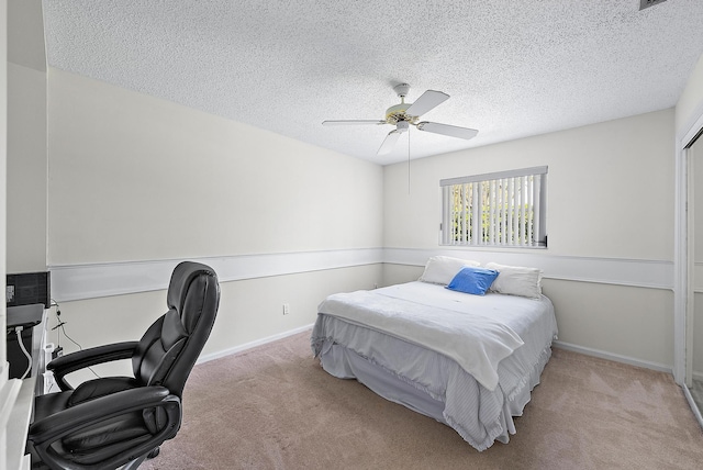 carpeted bedroom featuring baseboards, a textured ceiling, and a ceiling fan