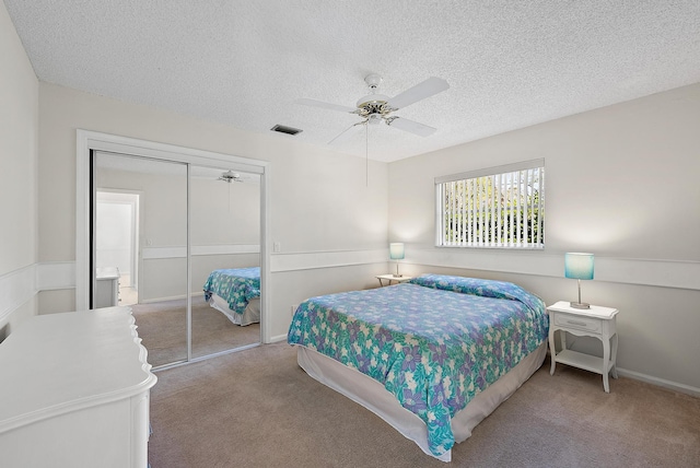 bedroom with visible vents, a textured ceiling, a closet, carpet flooring, and ceiling fan