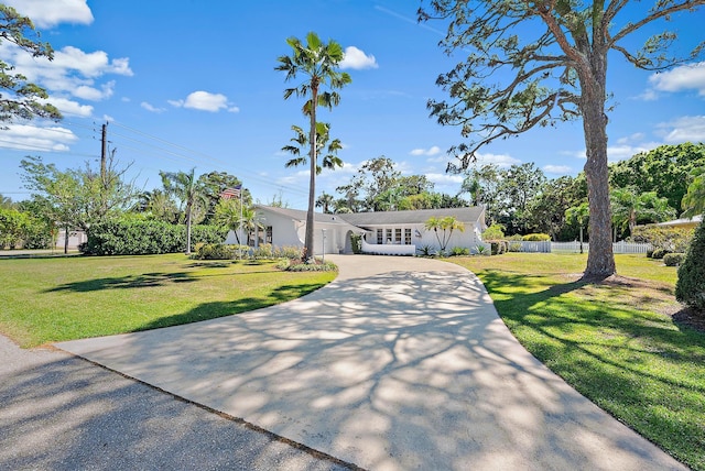 view of front facade featuring concrete driveway, fence, a garage, and a front lawn