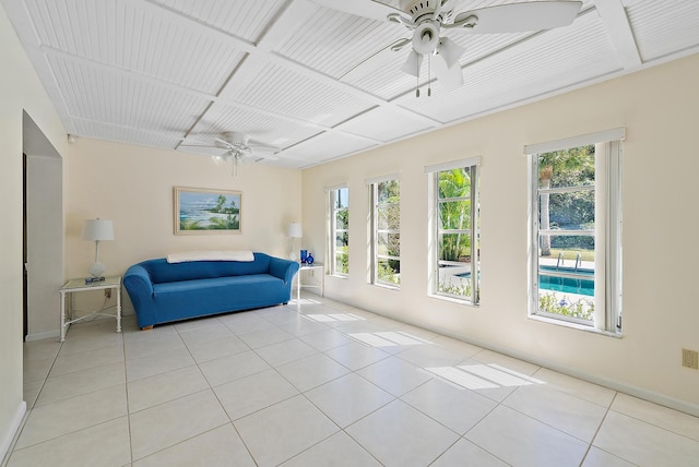 interior space featuring baseboards, coffered ceiling, light tile patterned flooring, and a ceiling fan