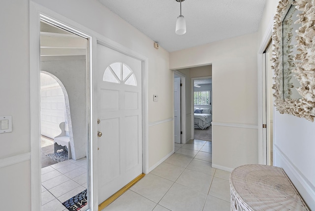 entryway featuring light tile patterned floors, baseboards, and a textured ceiling