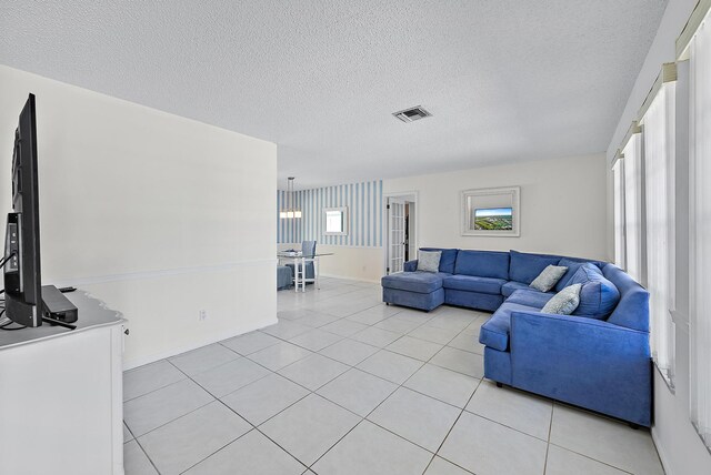 living room with light tile patterned floors, visible vents, baseboards, and a textured ceiling