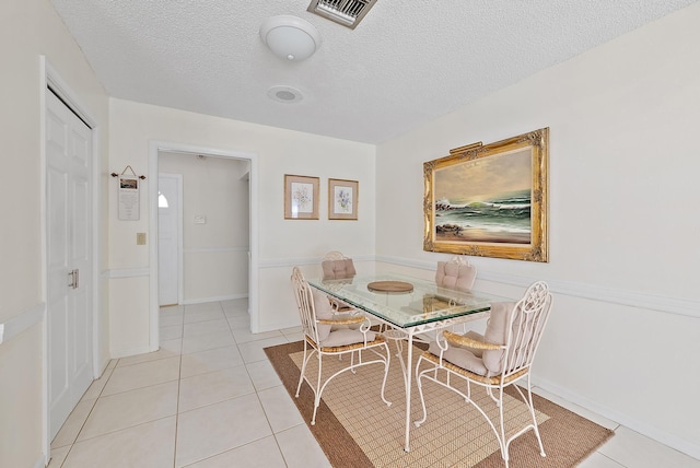 dining area featuring visible vents, a textured ceiling, and light tile patterned flooring