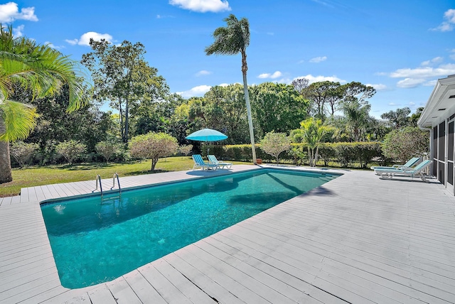 view of pool featuring a fenced in pool, a lawn, a deck, and a sunroom