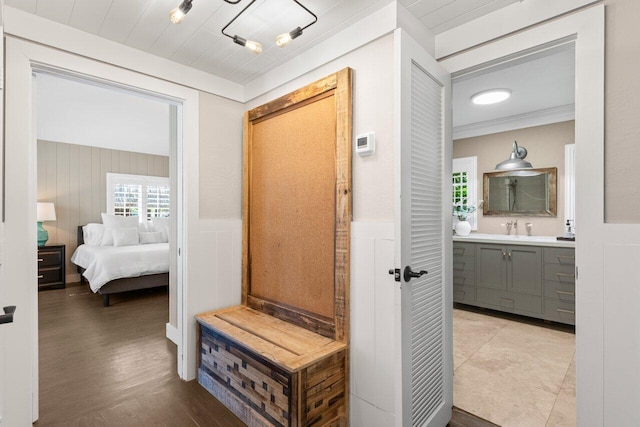 interior space with a wainscoted wall, wood finished floors, crown molding, and vanity