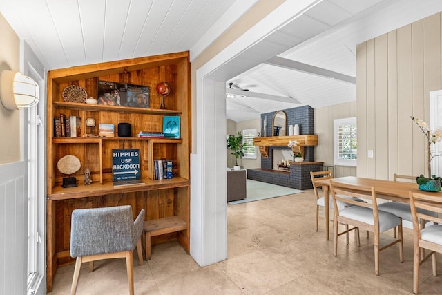 dining room featuring vaulted ceiling with beams, a brick fireplace, wooden walls, and built in features