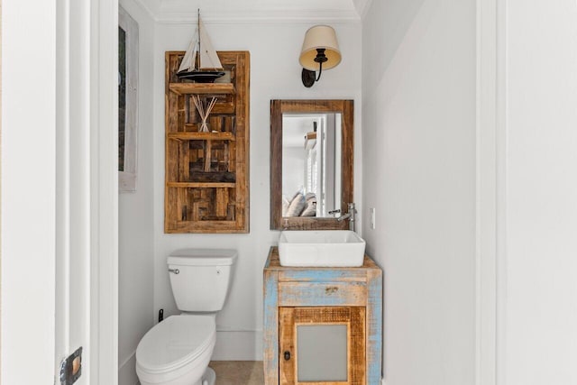 half bathroom with toilet, crown molding, and vanity