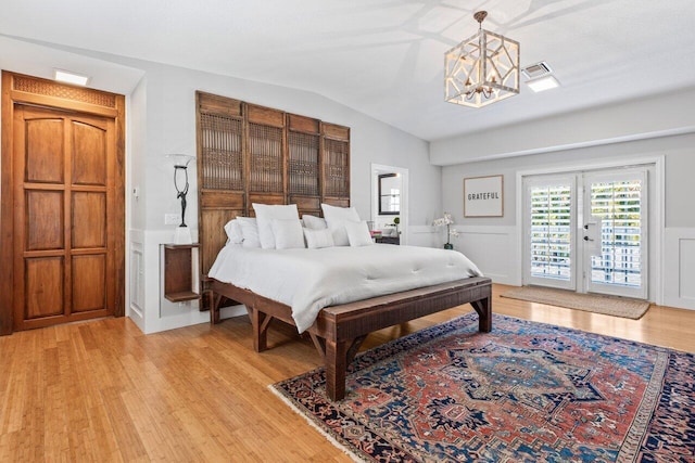 bedroom featuring lofted ceiling, visible vents, a decorative wall, light wood-style flooring, and access to outside