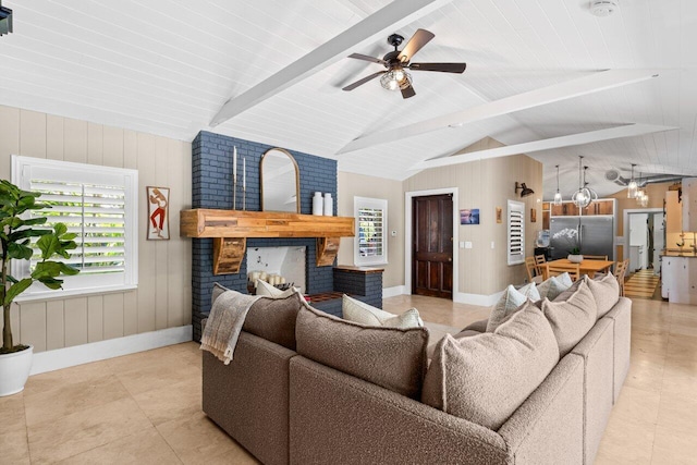 living area featuring lofted ceiling with beams, ceiling fan, wooden walls, a fireplace, and baseboards