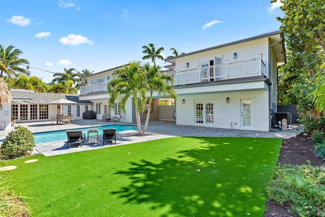 back of property with a balcony, stucco siding, and french doors