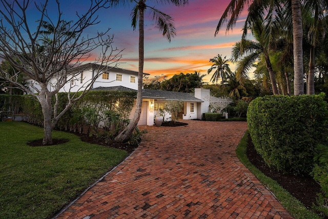 view of front of house with decorative driveway, an attached garage, and a front lawn