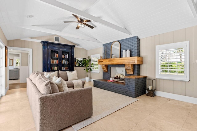 living room featuring visible vents, lofted ceiling with beams, ceiling fan, wood walls, and a fireplace