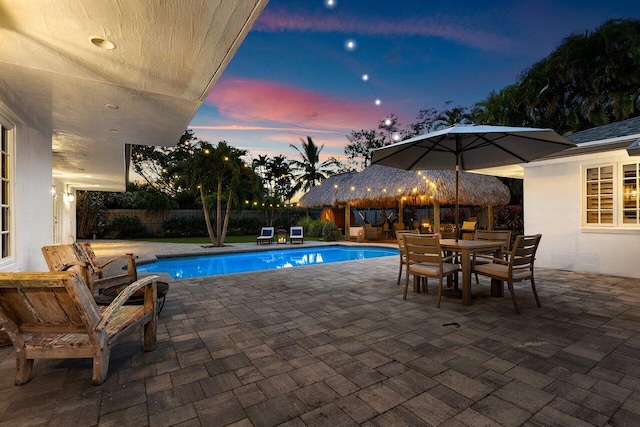 pool at dusk with a patio area, a fenced backyard, and a fenced in pool