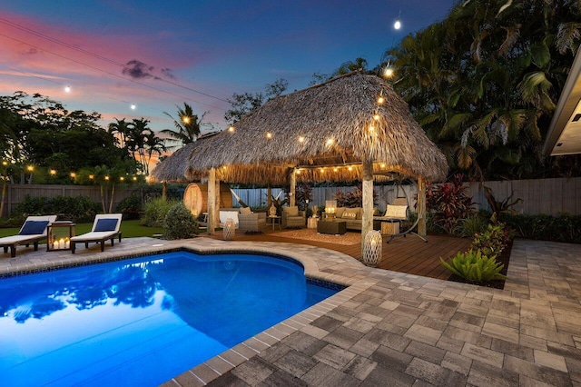 pool at dusk featuring a gazebo, a patio, outdoor lounge area, and a fenced backyard