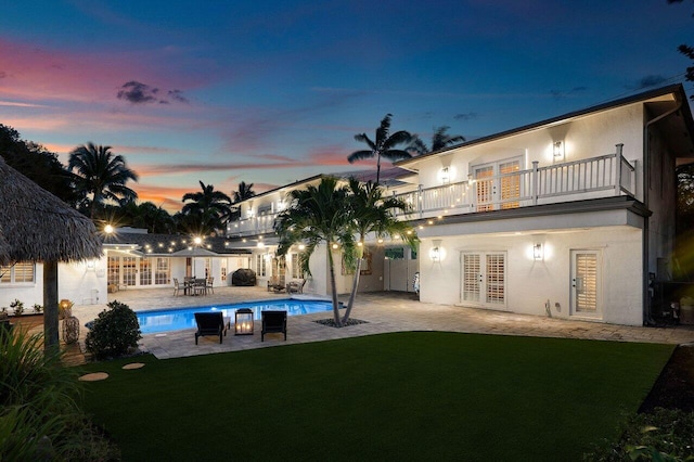 rear view of property featuring french doors, a patio area, a balcony, and stucco siding