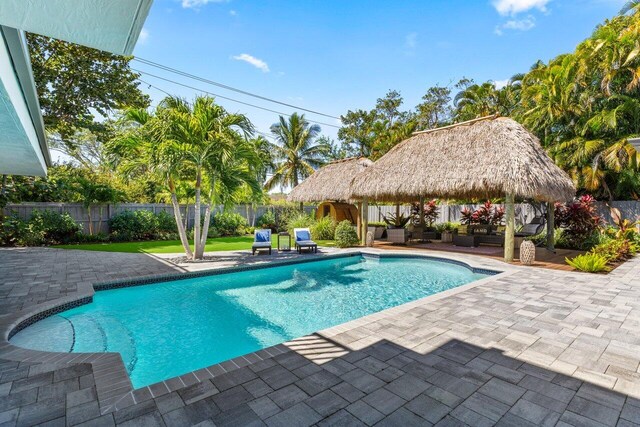 pool at dusk featuring a patio, outdoor dining space, outdoor lounge area, and a gazebo