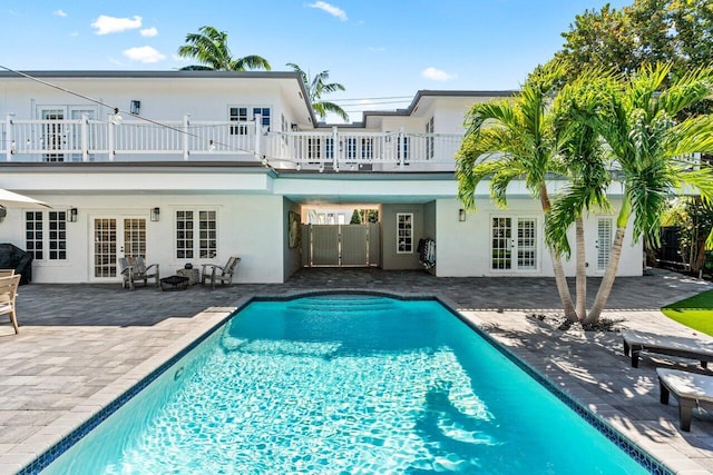 rear view of property with an outdoor pool, french doors, a patio, and stucco siding