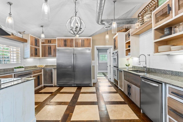 kitchen with a sink, a healthy amount of sunlight, appliances with stainless steel finishes, open shelves, and dark stone countertops