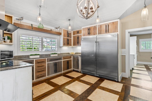 kitchen featuring baseboards, appliances with stainless steel finishes, brown cabinets, dark stone countertops, and open shelves