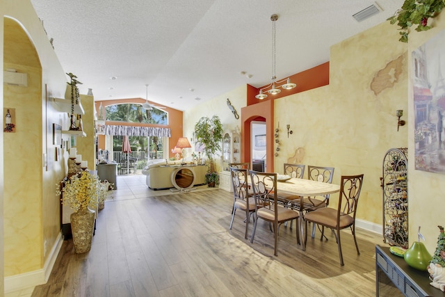 dining space with visible vents, arched walkways, vaulted ceiling, and wood finished floors