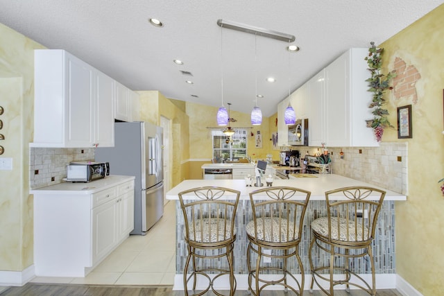 kitchen with light countertops, appliances with stainless steel finishes, a peninsula, and white cabinets