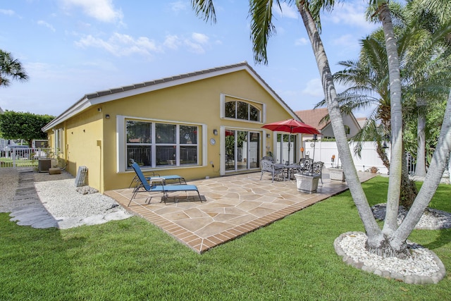 back of property featuring a patio, fence, a lawn, and stucco siding