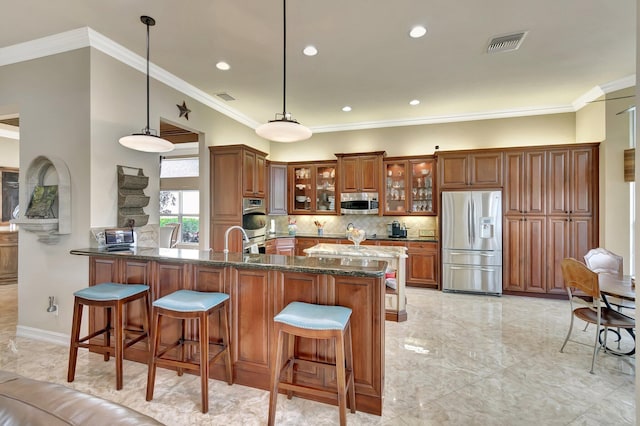 kitchen with visible vents, appliances with stainless steel finishes, brown cabinetry, and a kitchen breakfast bar