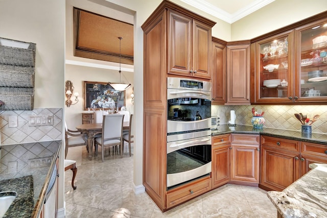 kitchen featuring double oven, glass insert cabinets, dark stone counters, and crown molding