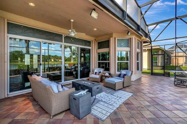 view of patio with a lanai, ceiling fan, and an outdoor living space with a fire pit