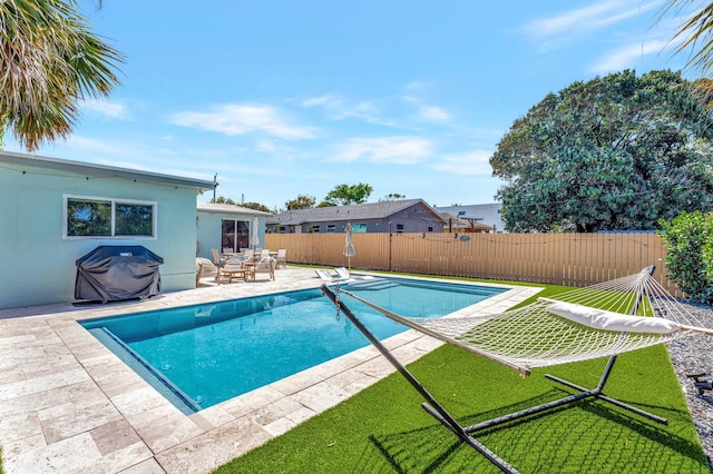 view of pool with a fenced in pool, a patio area, a lawn, and a fenced backyard