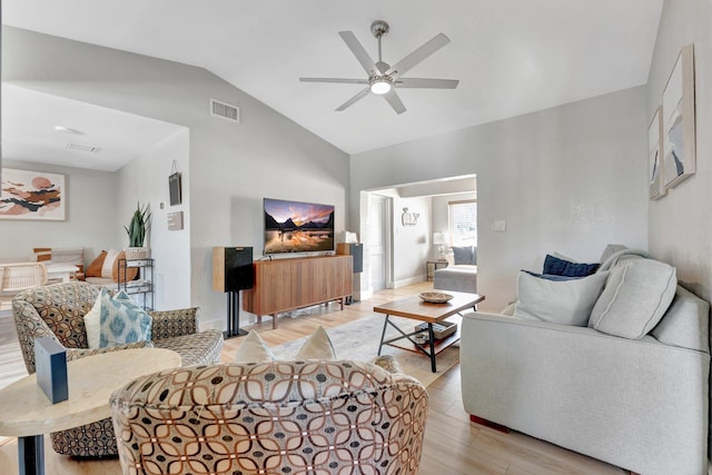 living room featuring vaulted ceiling, light wood finished floors, visible vents, and a ceiling fan