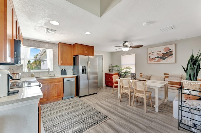 kitchen featuring stainless steel appliances, light countertops, a sink, and visible vents