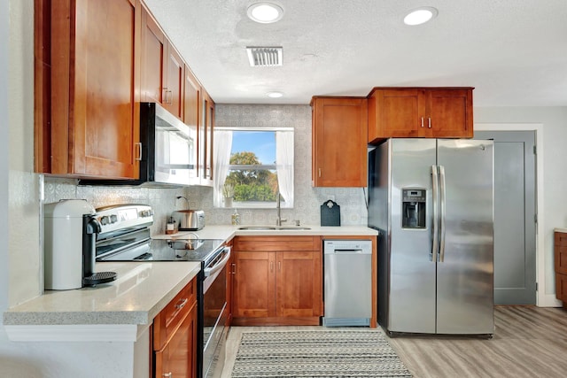 kitchen with tasteful backsplash, visible vents, stainless steel appliances, a textured ceiling, and a sink