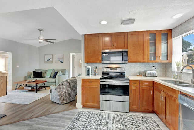 kitchen with visible vents, appliances with stainless steel finishes, vaulted ceiling, light countertops, and a sink