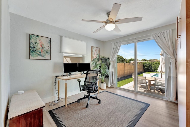 office area featuring a ceiling fan, baseboards, wood finished floors, and a textured wall