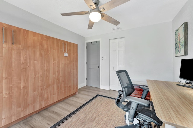 office area featuring baseboards, light wood-type flooring, visible vents, and a ceiling fan